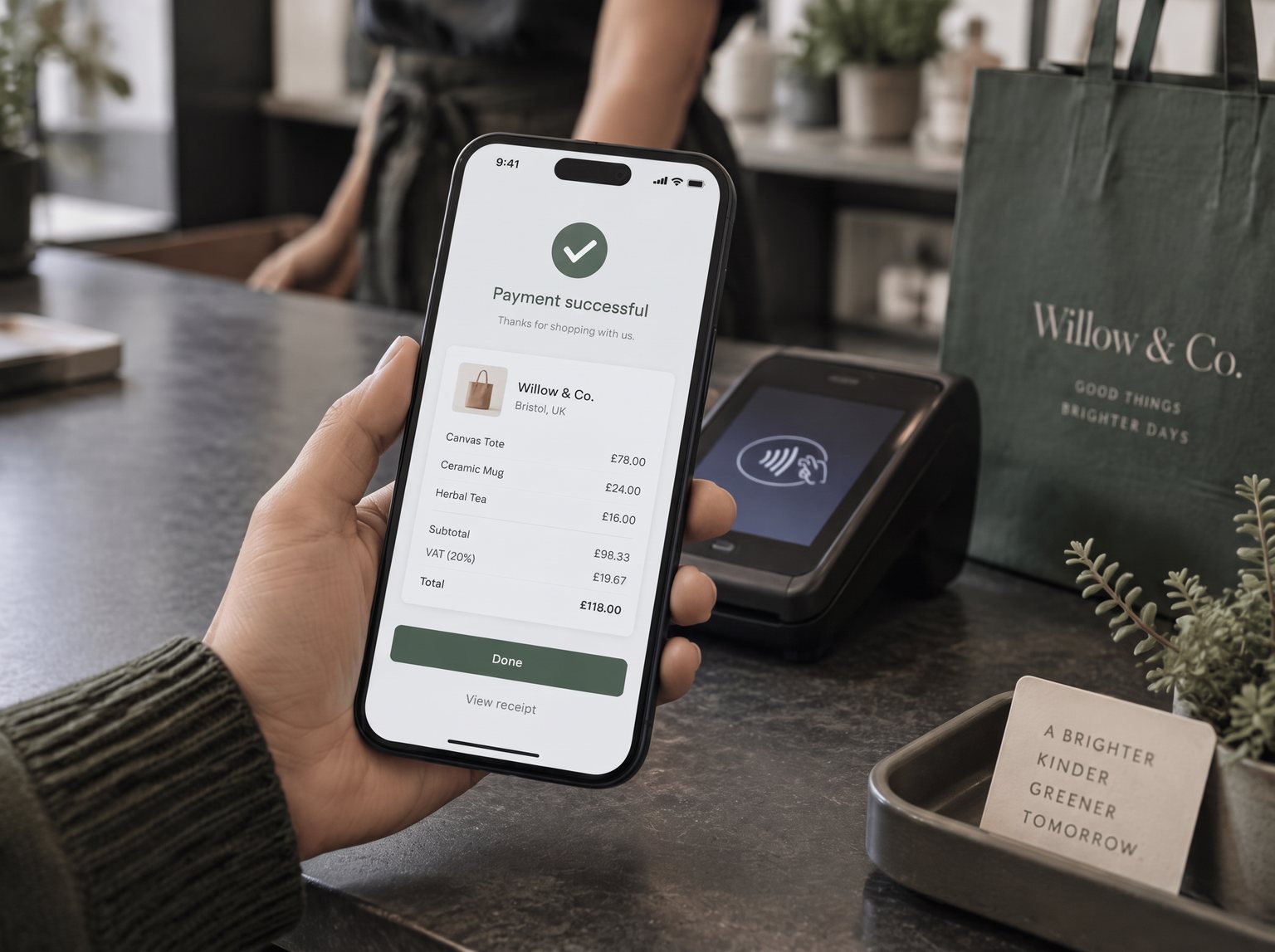 Shopper's phone showing a digital receipt with pound prices next to a card terminal at a UK boutique checkout